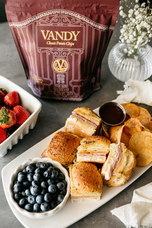 Warm, pull-apart ham and cheese sliders are brushed with a savory garlic butter and baked until melty served with Vandy Crisps