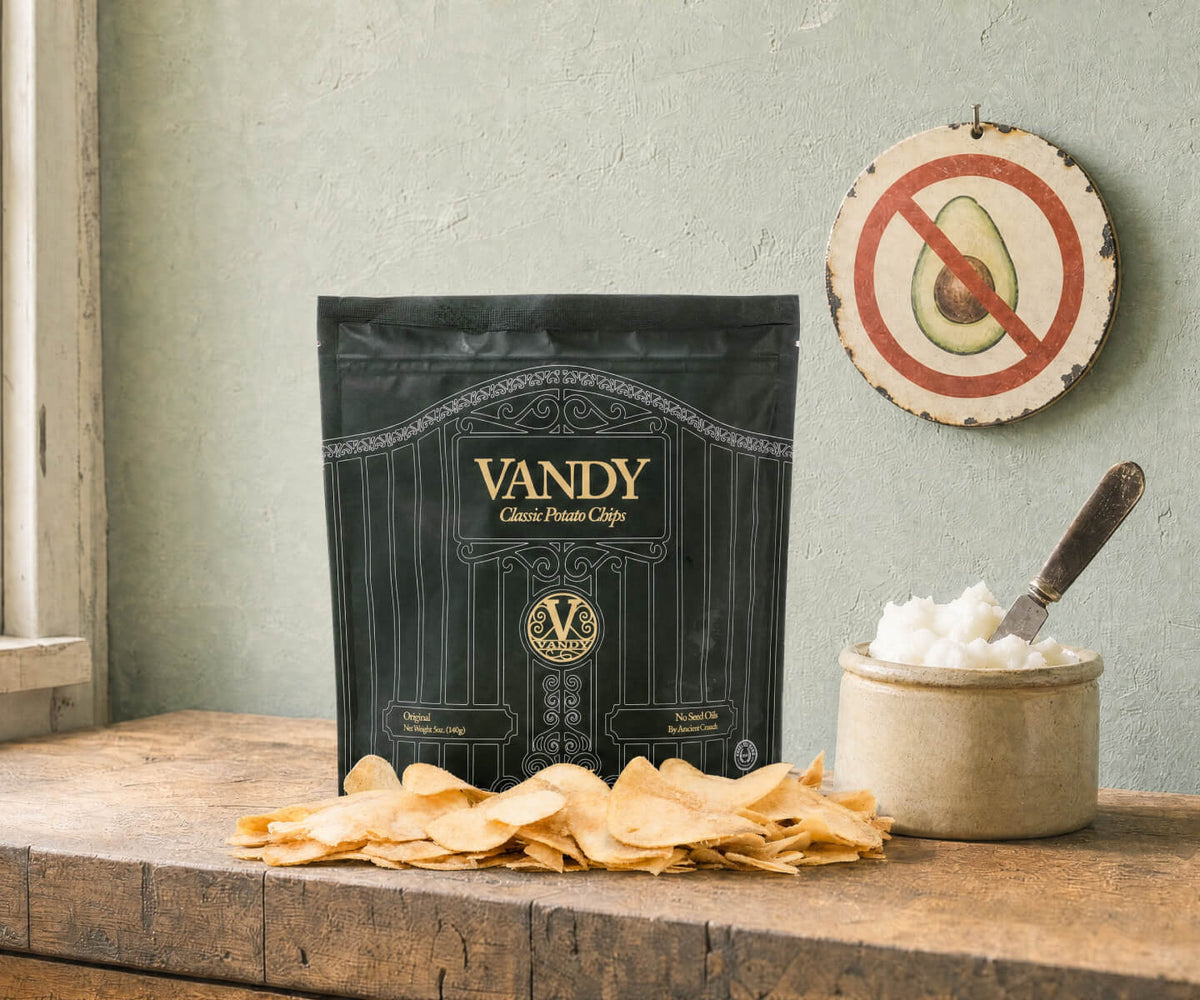 Bag of Vandy potato chips on a kitchen counter beside a crock of beef tallow, under a no-avocado-oil symbol